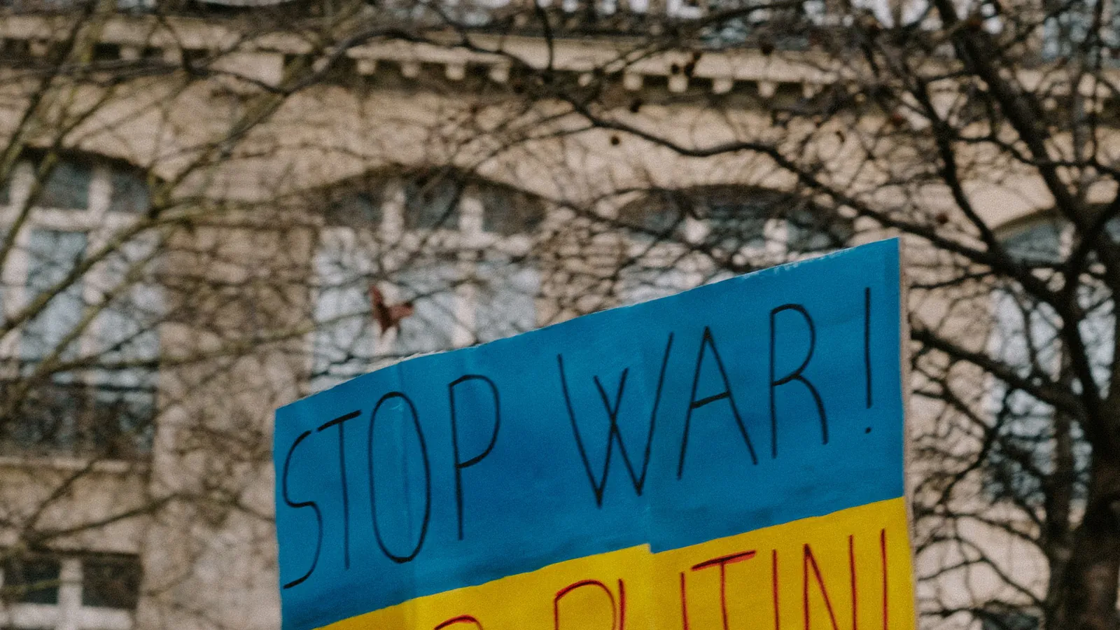 Manifestação com cartaz de protesto, referência a choques geopolíticos